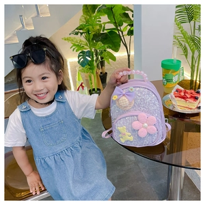 Détail d'un sac à dos violet à paillettes pour fille avec poignée en perles et breloques