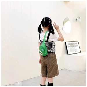 Close-up of a green shark canvas chest bag for kids with adjustable strap in a modern room