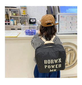 Rear view of a child wearing a black denim backpack with yellow letter printing