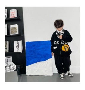 Détail d'un petit sac rond en nylon jaune vif porté avec un cardigan en tricot pour enfants