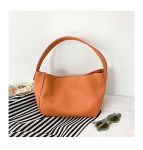 Detail of girls terracotta leather handbag featuring contrast white stitching and handle