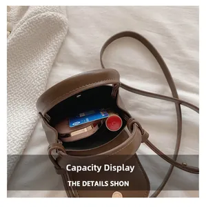 Internal capacity of mini brown leather crossbody bag showing makeup and cards