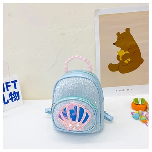 Detail of blue sequined mini backpack featuring shell ornament and pearl bead handle