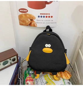 Detailed view of the cute cartoon penguin backpack made of black canvas in a shopping basket