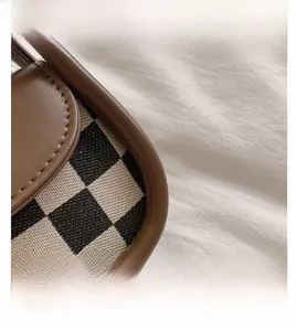 Detail view of the black and white checkered canvas texture with brown leather edging