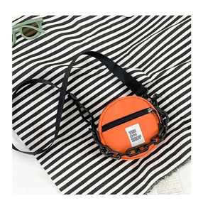 Détail d'un mini sac rond orange en nylon avec fermeture éclair et chaîne décorative