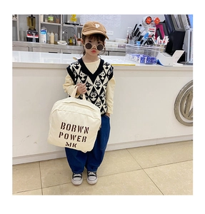 Detail of kids denim backpack styled with knit vest and casual trendy outfit