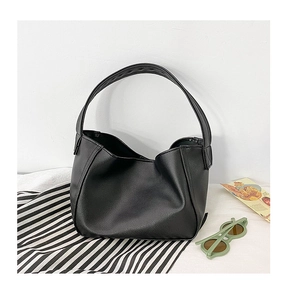 Detail of minimalist black faux leather mini dumpling bag for girls with soft pleats