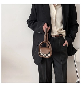 Close-up of a mini checkered crossbody bag with brown leather trim and adjustable strap