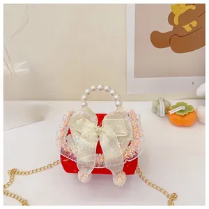 Detail of red girl's mini handbag with pearl handle and sequins bow decoration