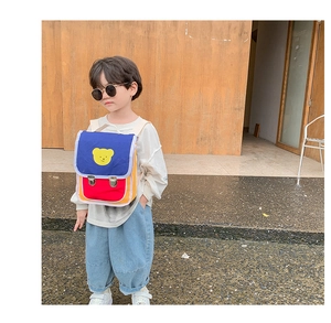 Photo en extérieur d'un enfant portant le sac à dos ours tricolore avec détails bleu et rouge