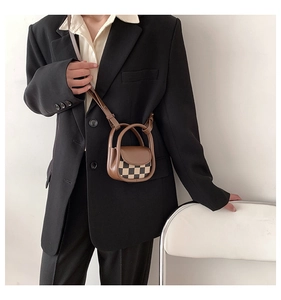 Close-up of a mini brown checkerboard crossbody bag with round handles on a model