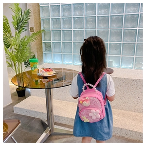 Détail du mini sac à dos rose pour enfant avec poignée en perles et fleurs en 3D