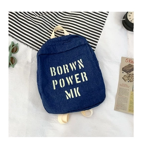 Detail of dark blue denim kids backpack featuring yellow letter print and beige straps