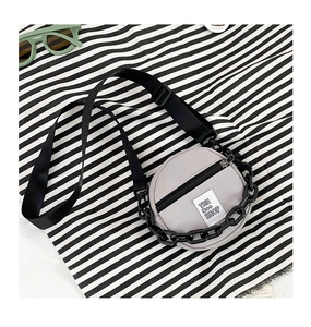 Détail du sac bandoulière rond en nylon gris clair avec chaîne noire et sangle réglable