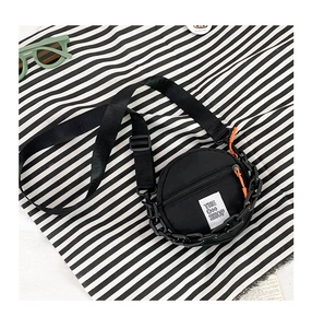 Détail du sac rond en nylon pour enfants avec chaîne noire et écusson blanc