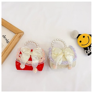 Close-up of elegant kids' handbags with large organza bows and pearl handles in red and beige