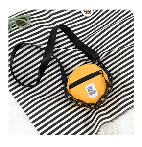 Détail du sac rond jaune en nylon pour enfants avec chaîne noire et étiquette tissée