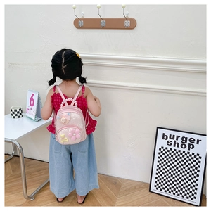 Sac à dos rose à paillettes pour enfant avec fleurs et ours porté par une fille