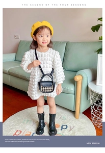 Girl wearing white bubble dress and yellow beret with a checkerboard crossbody bag