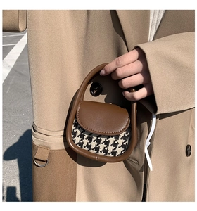 Detailed macro view of mini houndstooth handbag with brown leather trim and handle