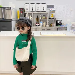 Girls fashion set featuring green ribbed knit sweater, leather skirt and beige crossbody bag