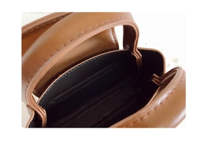 Detailed macro view of brown leather bag interior with black lining and stitching