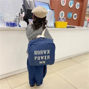 Kids denim backpack in navy blue with bold letter print worn by a child model