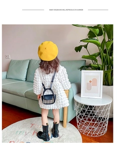Detail of child wearing white textured dress with black and white houndstooth crossbody bag