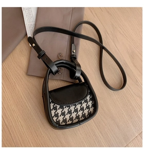 Detailed top view of a mini houndstooth crossbody bag with leather trim on wood surface