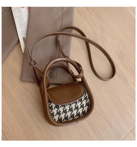 Detail of mini houndstooth crossbody bag with brown leather trim and round top handle