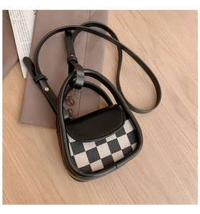 Detail of mini checkerboard crossbody bag with black leather trim and long shoulder strap