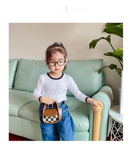 Close-up of mini checkered crossbody bag on a child model wearing a white knit top