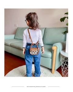 Mini checkered girl's crossbody bag with brown leather accents shown on a child model