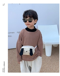 Close-up of a child wearing a beige canvas dog pattern chest bag with purple zipper detail