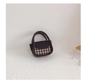 Mini handbag detail showing black leather and houndstooth texture with double handles