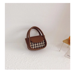 Detail of mini houndstooth handbag with brown leather trim and retro stitch craftsmanship