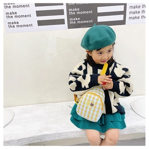 Gros plan d'un sac de poitrine enfant à carreaux jaunes avec écusson ours sur un mannequin