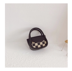Detailed view of mini leather handbag with black and white checkerboard pattern flap