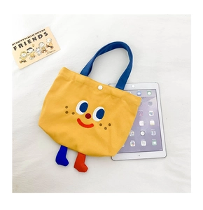 Detailed view of yellow canvas bag with cartoon embroidery, 3D feet, and snap button closure