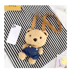Détail du sac à bandoulière peluche ours avec salopette en jean sur un fond texturé