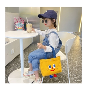 Detail of yellow canvas tote bag featuring cute cartoon smiley face and 3D foot accents