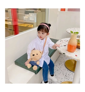 Enfant en chemise blanche et jean avec un joli sac bandoulière ours en peluche au café