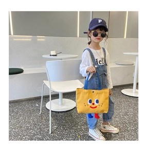 Close-up of yellow canvas kids bag with cute cartoon face and soft 3D leg details
