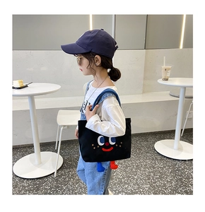 Close-up of black canvas bag with cute cartoon smile embroidery and 3D plush legs