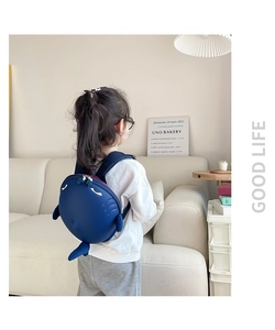 Toddler girl wearing a 3D shark shell backpack in navy blue with fins and tail detail