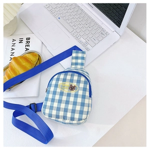 Détail du sac de poitrine à carreaux bleus avec badge d'ours et sangle en nylon