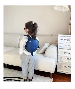 Detail of blue shark hardshell backpack worn by a toddler in a home setting