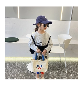 Close-up of cute off-white canvas tote bag with cartoon face and 3D feet for girls