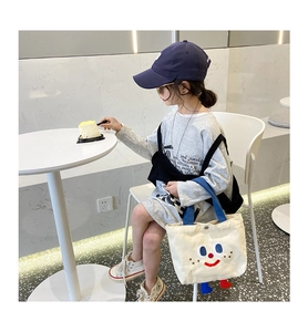 Detail of canvas kids tote bag featuring cartoon smile print and 3D feet decorations